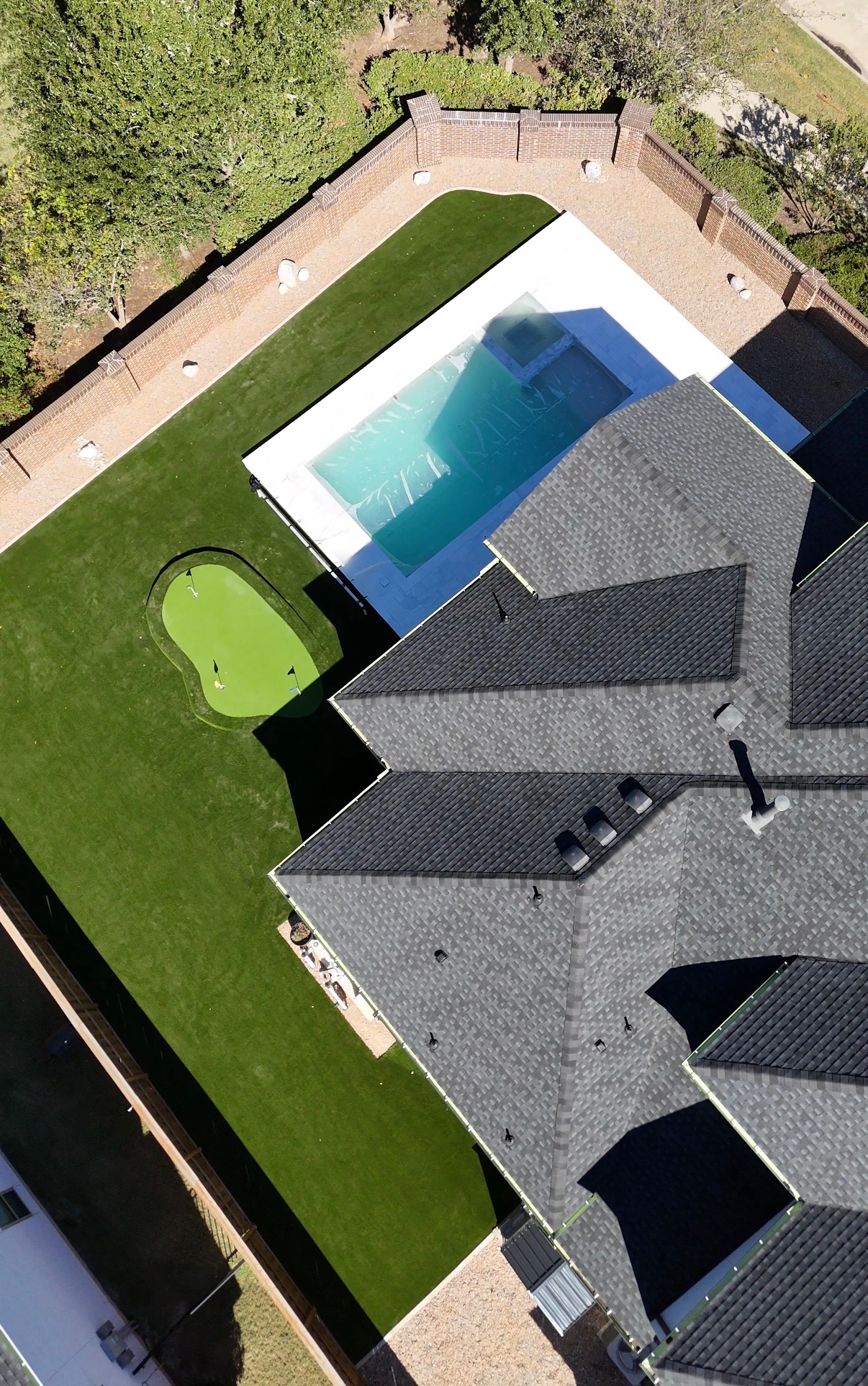 Aerial view of luxury Houston backyard with putting green, pool and full artificial turf lawn